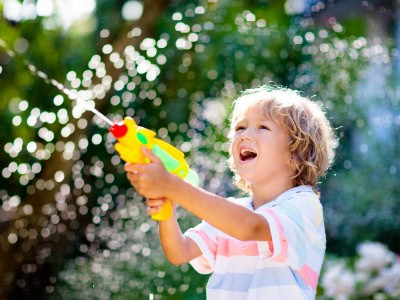 Young child playing with a water gun outdoors at Thrive Childcare, enjoying fun and engaging activities for early childhood development.
