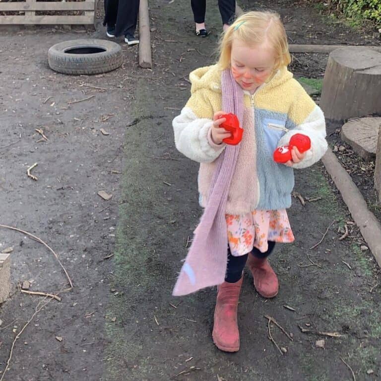 Soft pastel-coloured toddler outdoor play area at Thrive Childcare, featuring children engaging in sensory and hands-on activities in a safe, nurturing environment.