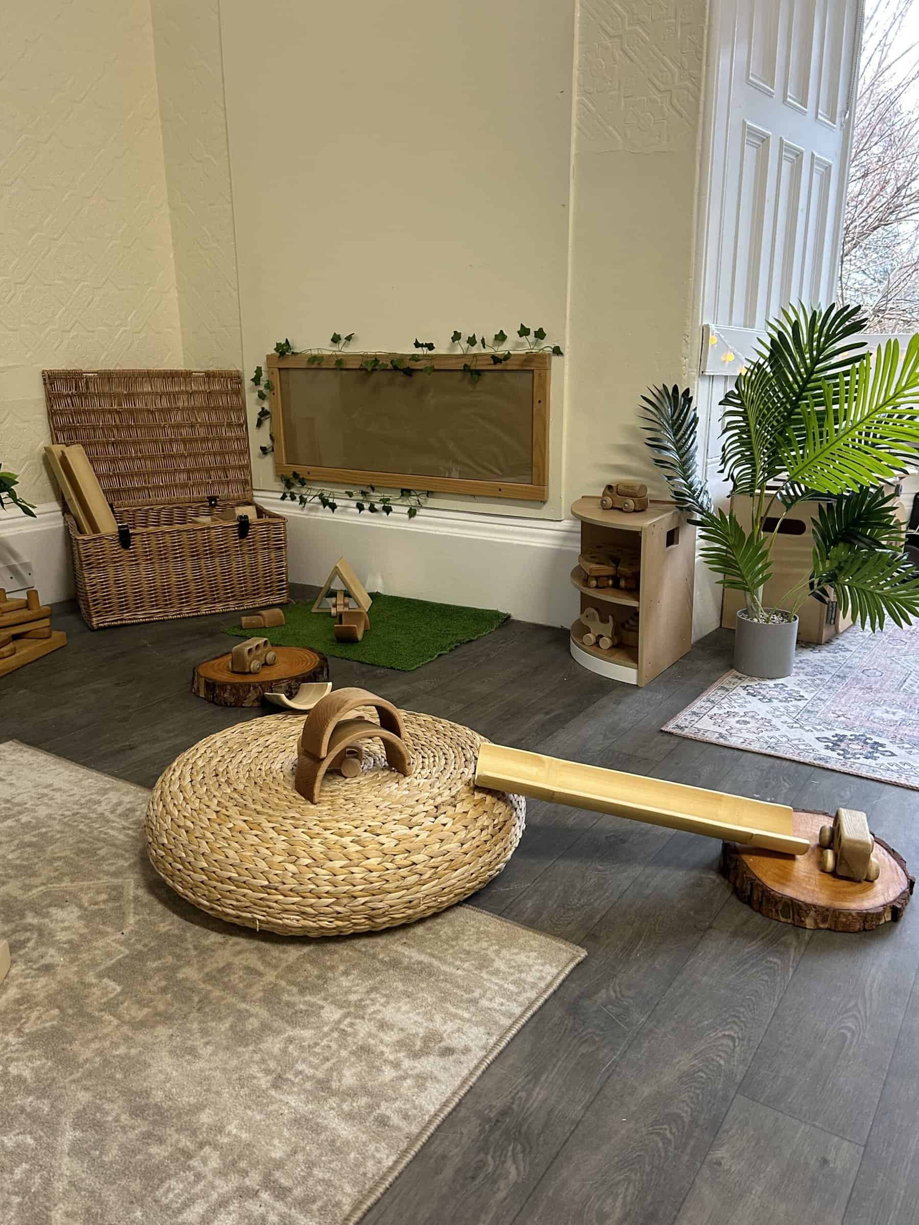 Bright indoor play area designed for young children with natural wooden toys, cozy rugs, and greenery, creating a safe and stimulating environment for early childhood development at Thrive Childcare.