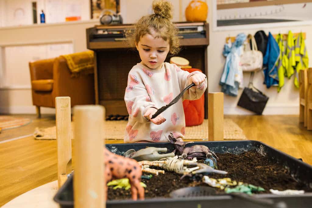 1. Young girl engaging with pretend play in a childcare setting, exploring animals in a themed educational activity at Thrive Childcare, promoting early learning and sensory development.