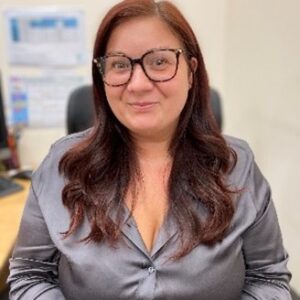 A caring childcare professional with glasses smiling in a childcare setting, promoting quality early years education at Thrive Childcare.