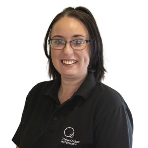 Caring childcare professional wearing black Thrive Childcare polo shirt, promoting trusted early childhood education and nurture for children's development.