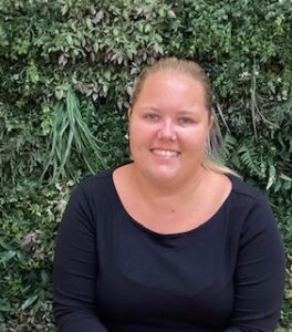 Bright smiling childcare professional outdoors at Thrive Childcare, nurturing early childhood development with caring staff and a safe environment for young learners.