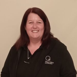 Energetic childcare educator at Thrive Childcare, smiling confidently in professional uniform, dedicated to early childhood education and nurturing young children in a safe learning environment.