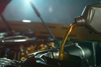 Engine oil being poured into a car engine for maintenance or repair.