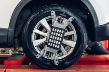 Car wheel alignment being performed with specialized equipment.