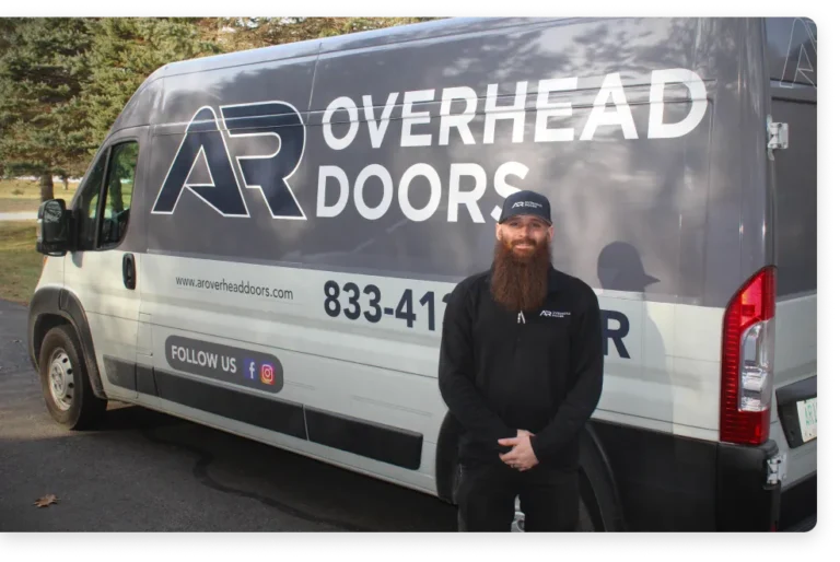 Man with a beard stands in front of an "AR Overhead Doors" service van.