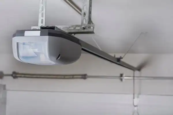 Ceiling-mounted automatic garage door opener with a metal track extending towards the door, offering reliable Overhead Door Operator Service.