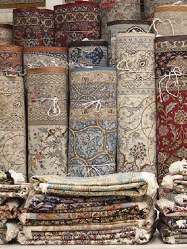 Variety of Persian rugs are rolled and stacked.