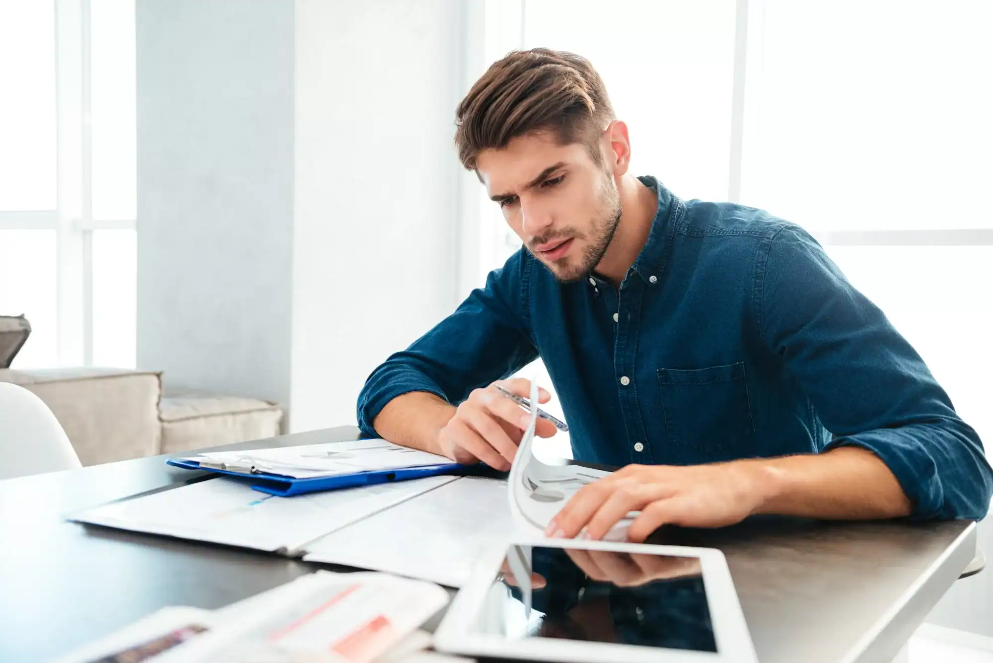 Busy young man sitting at home and thinking about finances