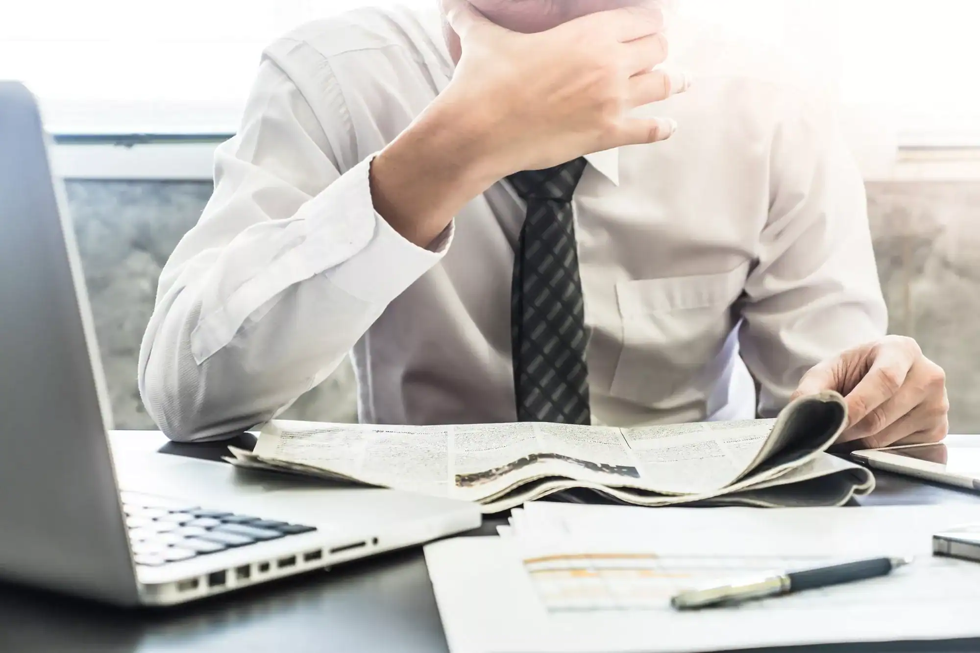 Close up of Frustrated Businessman reading newspaper on the desk.