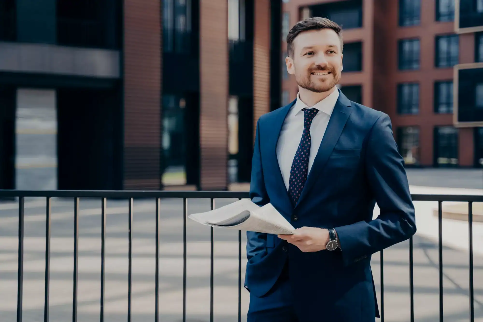 Happy office worker on break standing while holding newspaper