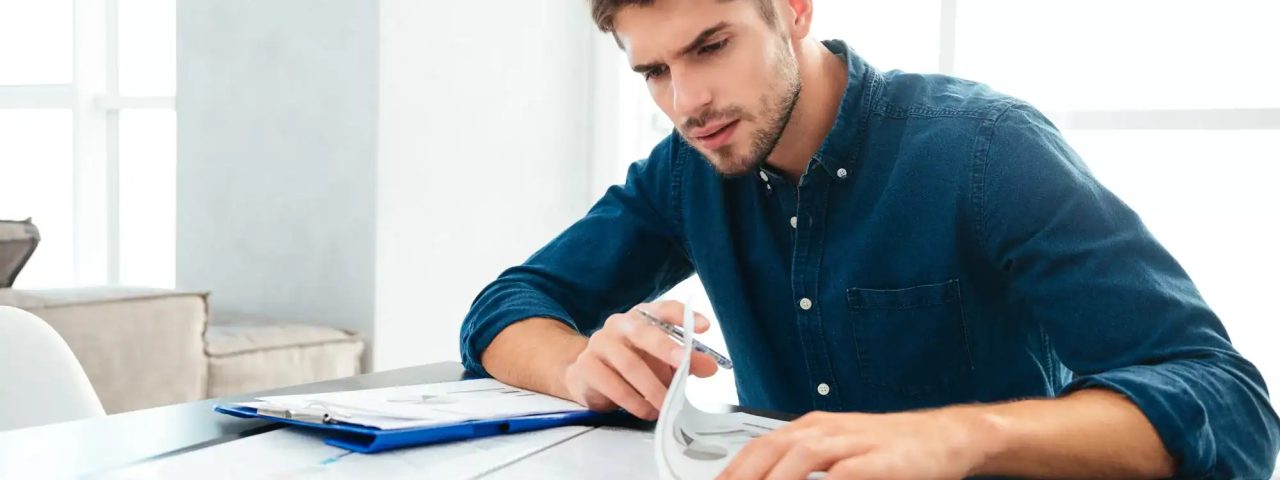 Busy young man sitting at home and thinking about finances