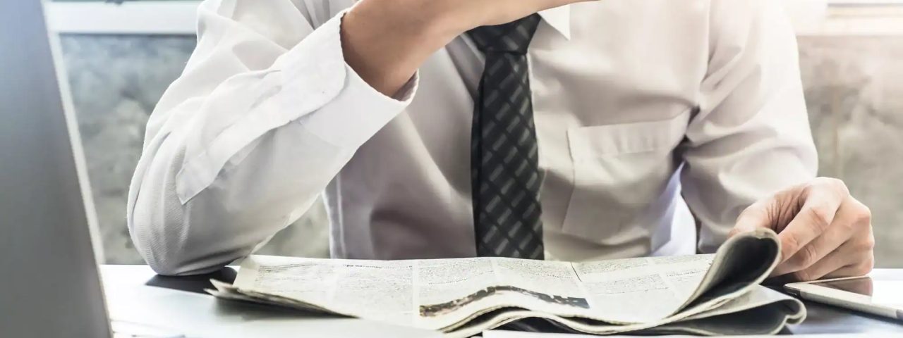 Close up of Frustrated Businessman reading newspaper on the desk.