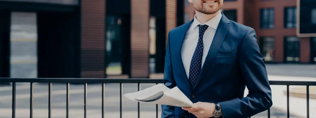 Happy office worker on break standing while holding newspaper