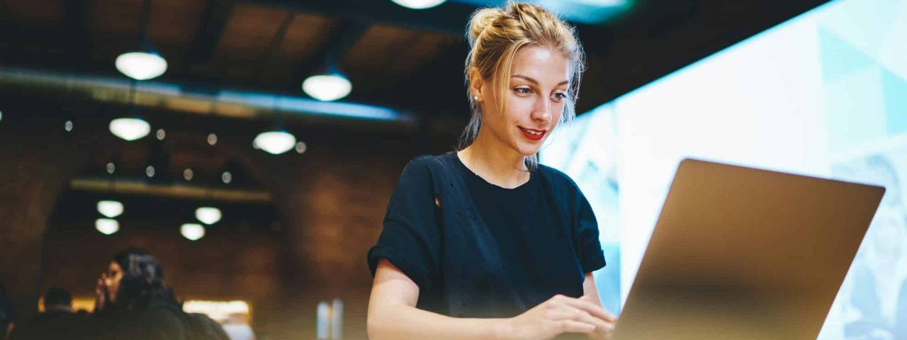 Skilled female freelancer making online booking and banking via netbook connected to coworking inter