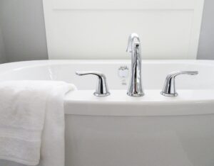 Close-up of a white bathtub with chrome faucet and handles, with a folded white towel draped over the side—a fresh look inspired by Bathroom Cleaning Tips for St. Paul and Minneapolis homes.