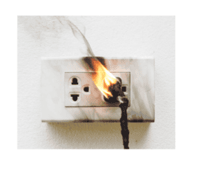 An electrical outlet with a plugged-in cord is on fire, emitting smoke and showing burn marks on the wall—urgent electrical outlet repair or replacement may be needed in the Twin Cities.