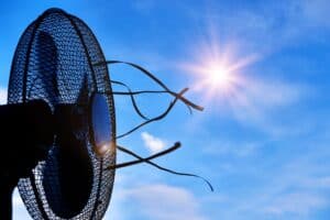 A black electric fan with cut power cords is photographed against a bright blue sky and sunny background, evoking an end of season vibe as you check your cooling appliances off the checklist.