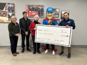 Five people pose indoors with a $43,500 donation check to the Minnesota Breast Cancer Coalition, joined by someone in a HERO mascot costume from Hero Home Services.
