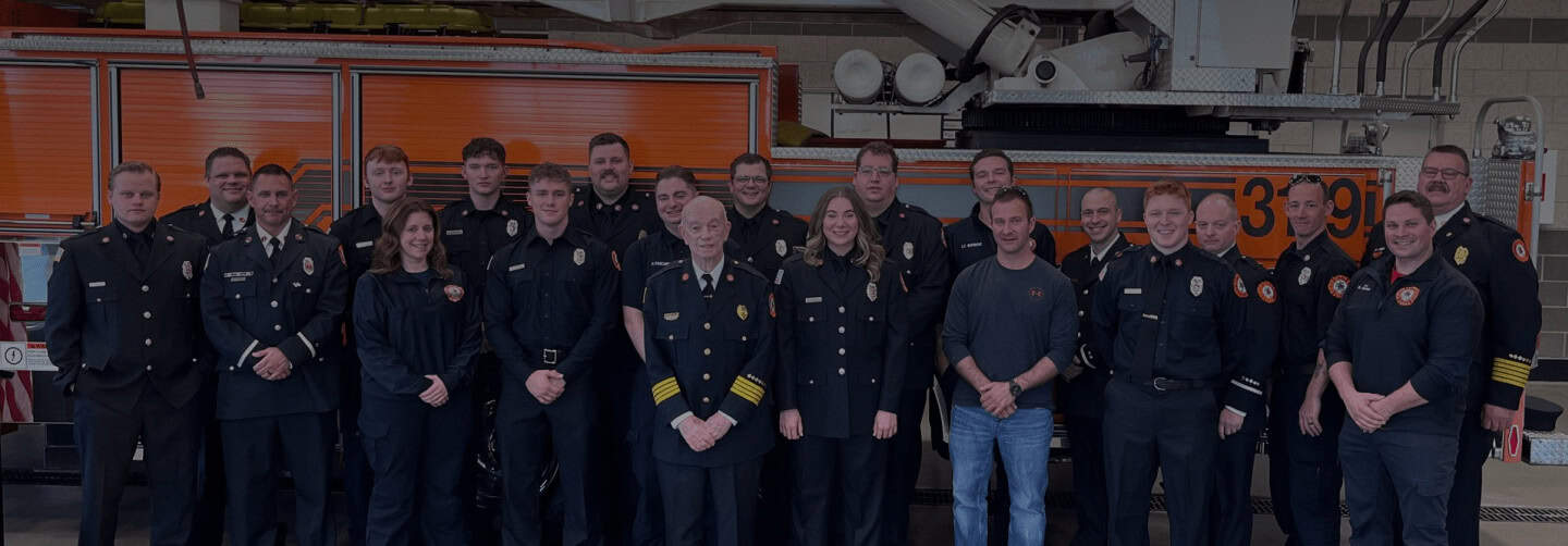 Group of firefighters posing in front of fire truck
