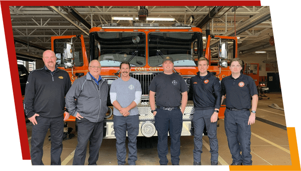 Firefighters posing with fire truck in station