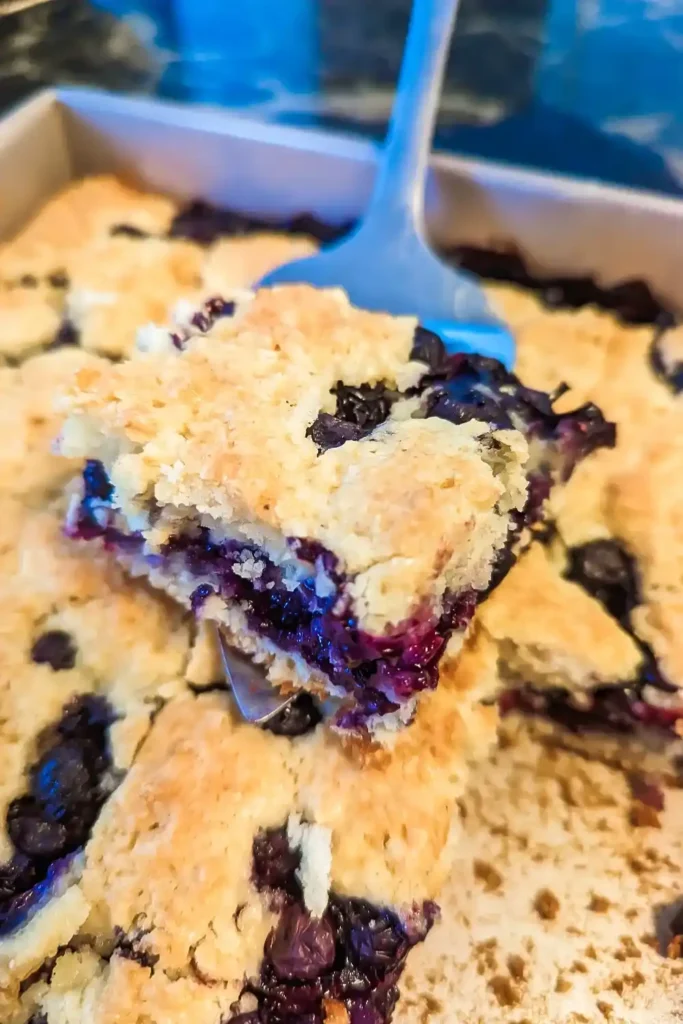 lifting one of the blueberry crumble squares from the baking pan