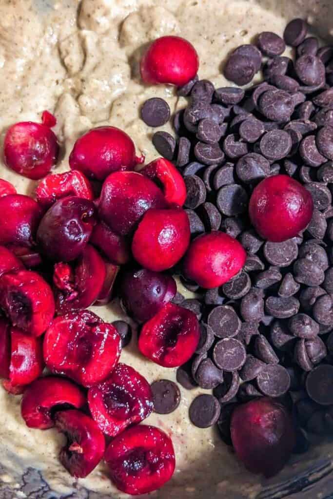 pitted halved fresh cherries and chocolate chips in muffin batter bowl