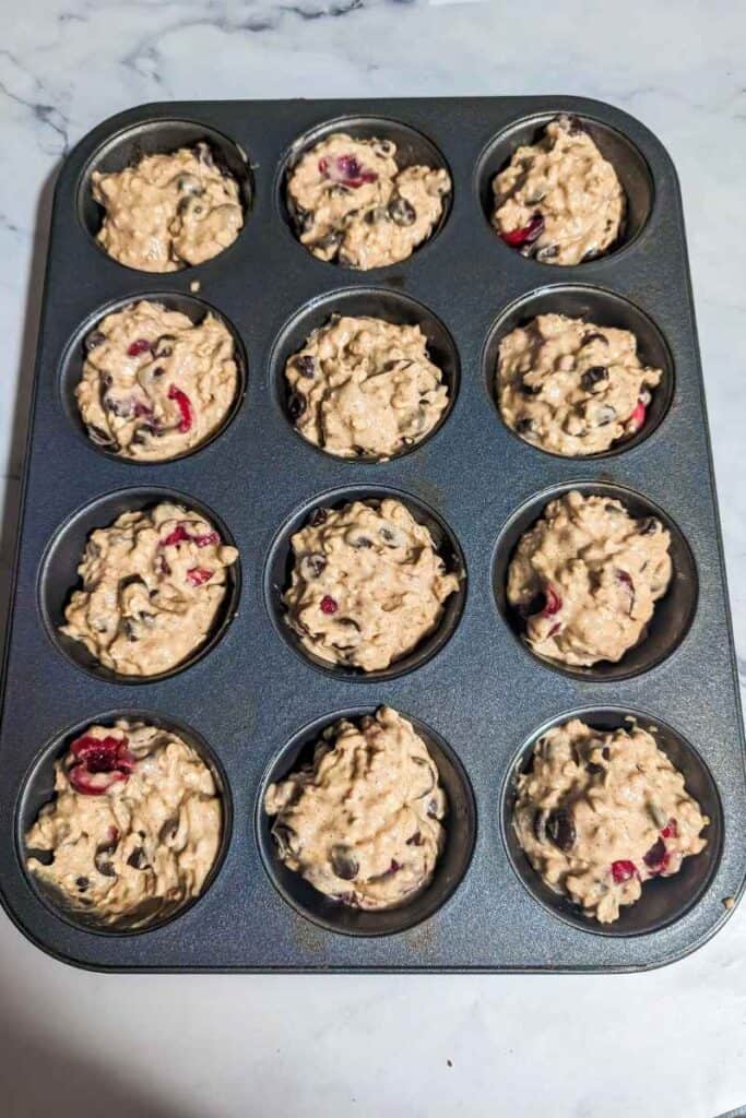 filling the muffin tin with the chocolate cherry oatmeal batter