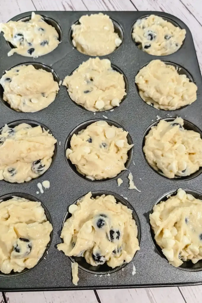 filling the muffin tins with the blueberry lemon cheesecake muffin batter
