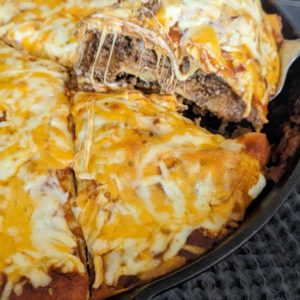 Layered cheesy Mexican taco bake in cast iron pan