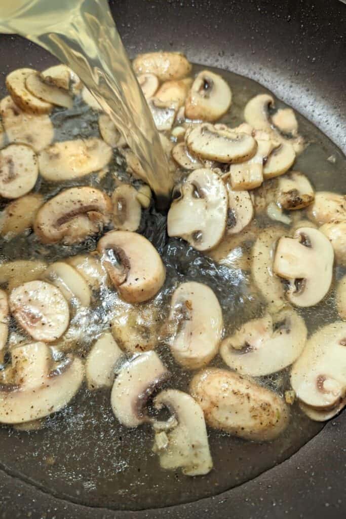 add chicken stock to sauteed mushrooms and garlic