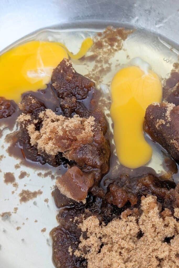adding eggs to brown sugar oil in bowl