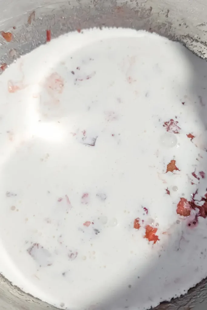 adding cream to strawberry rhubarb ice cream base