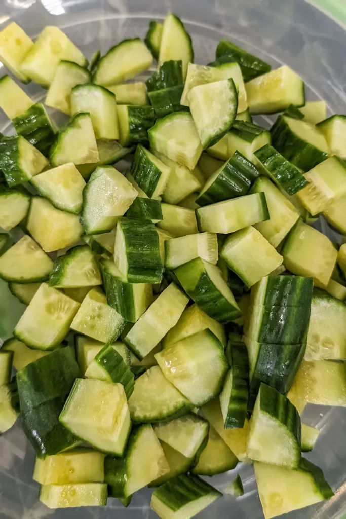 adding diced cucumber to salad bowl