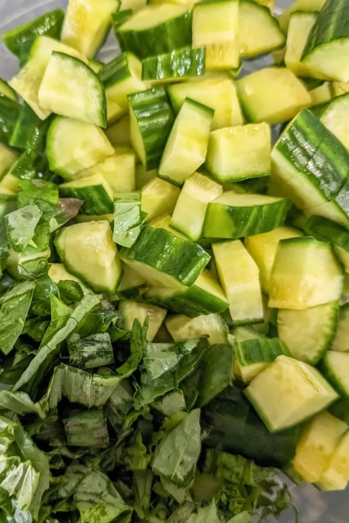 adding fresh basil to salad with cucumber
