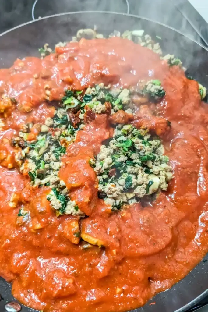 adding the jarred tomato basil pasta sauce to the sausage mixture