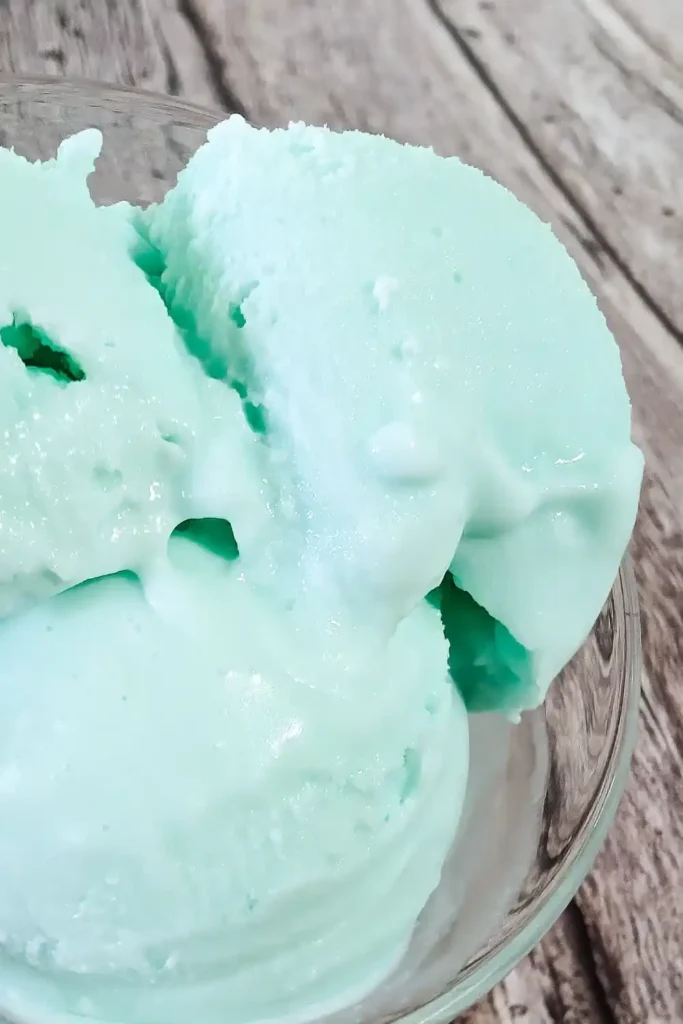 blue raspberry ice cream scooped into a glass dessert cup off set from image