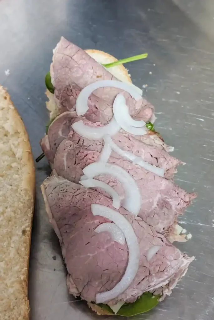 adding onion and roast beef to sub