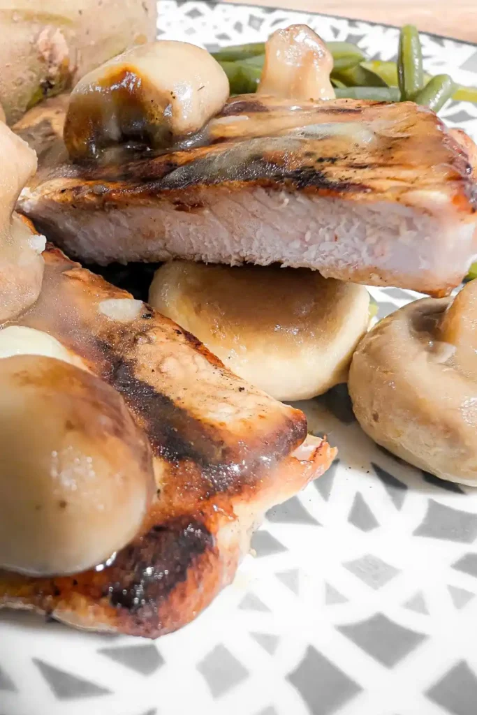 close up of grill pork chop well done cut open with button mushroom sauce