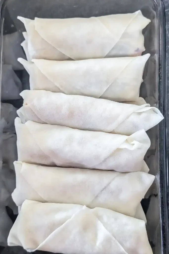 finished uncooked shrimp spring rolls stacked in dish