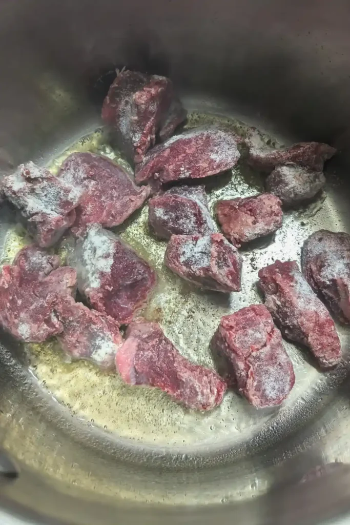 adding floured stew meat to the pot