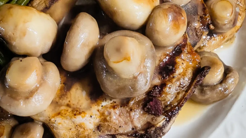 featured image of golden button mushroom sauce over grilled bone-in pork chops