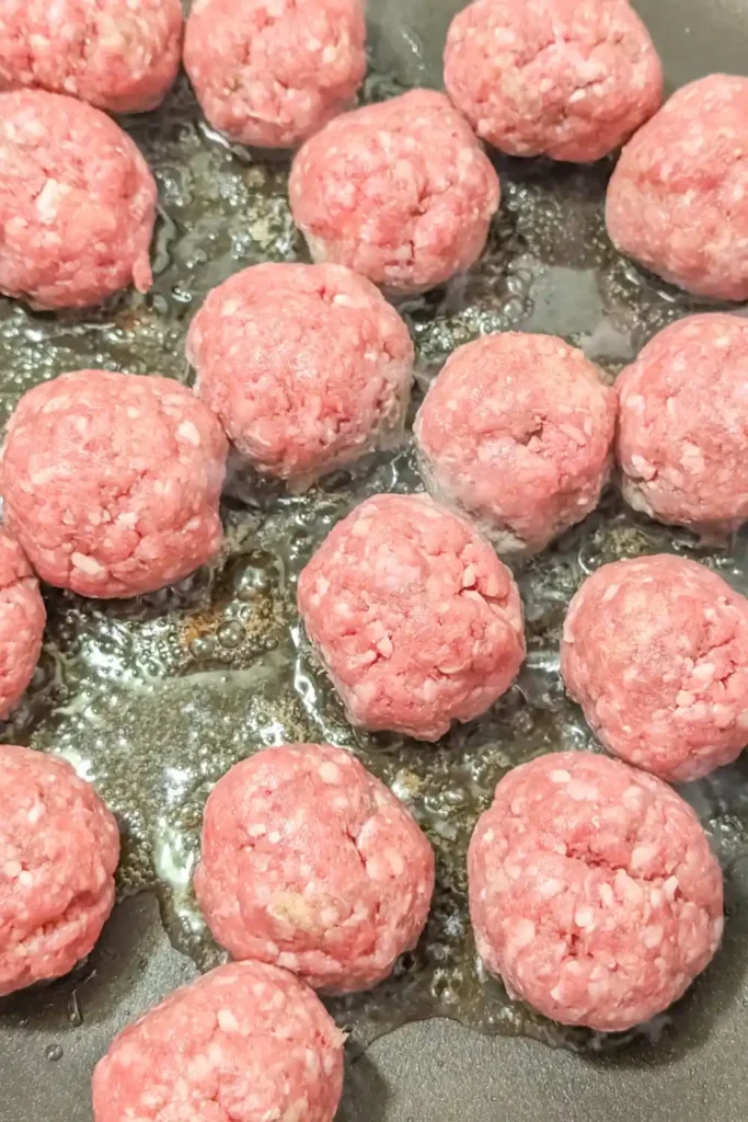 raw meatballs in non-stick frying heated with neutral oil