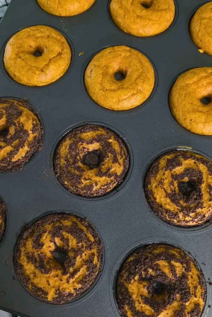 baked pumpkin donuts with some plain some covered in chocolate cookie crumbs