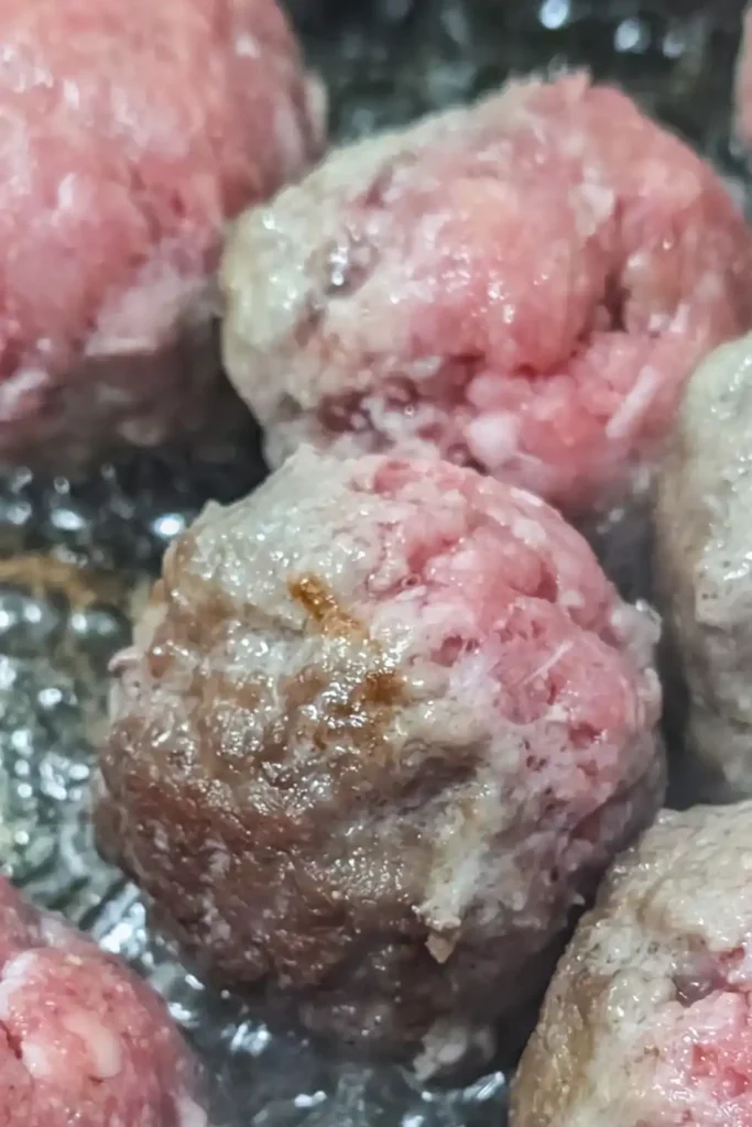 close of browning meatballs in neutral oil in non-stick frying pan