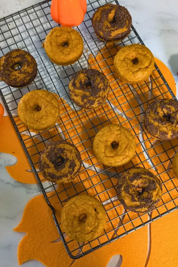 baked pumpkin donuts on wire cooling rack with orange maple leaf placemat under the rack