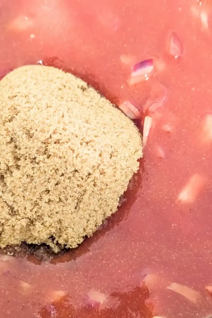 adding brown sugar to bbq sauce in bowl