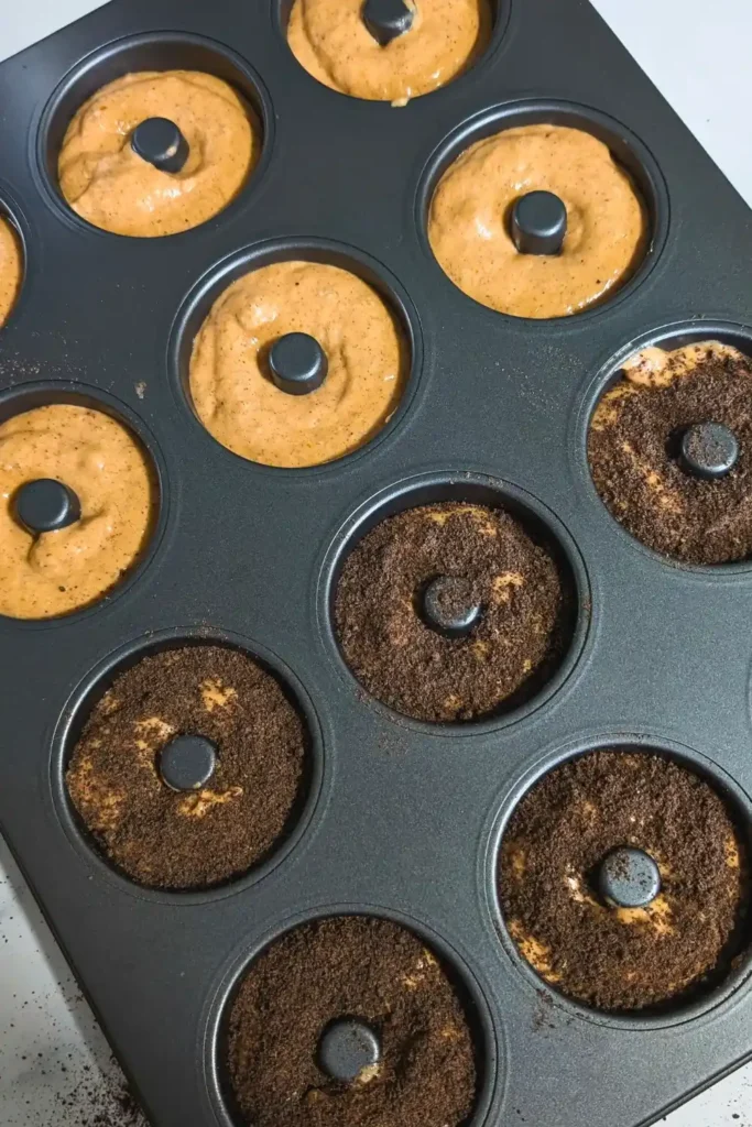 full pumpkin donut pan with half plain half covered in chocolate cookie crumbs