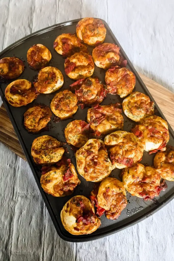 baked mini pizza muffin rolls in mini muffin pan on wood cutting board